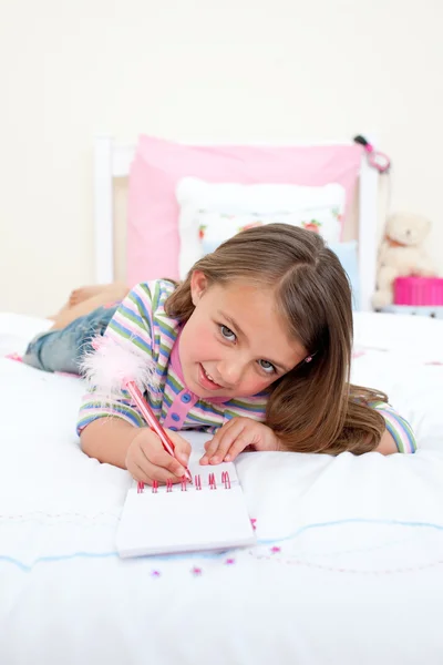 Мила маленька дівчинка пише на блокноті — стокове фото