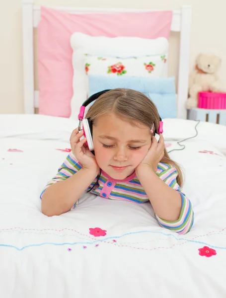 Красива маленька решітка слухає музику, що лежить на її ліжку — стокове фото