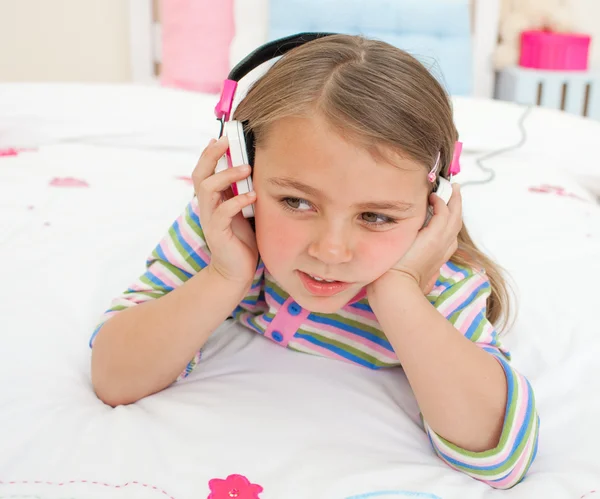 Adorable gril listening to music lying on her bed — Zdjęcie stockowe