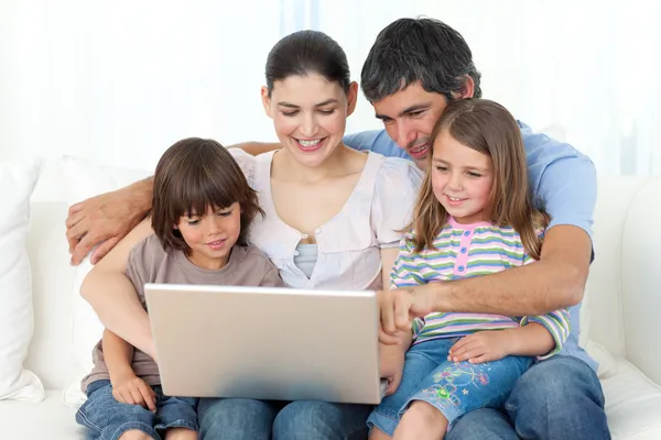 Famiglia Jolly utilizzando un computer portatile sul divano — Foto Stock