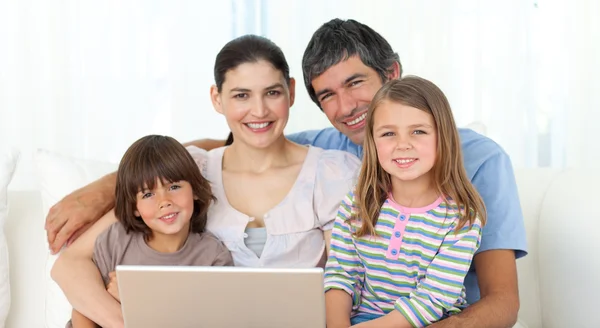 Met behulp van een laptop op de Bank en gelukkige familie — Stockfoto
