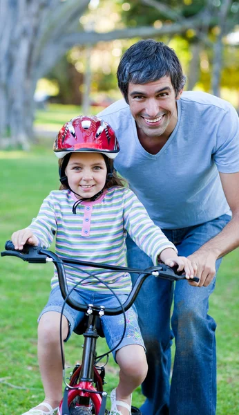 Sevimli küçük kız babasıyla birlikte Bisiklete binmek için öğrenme — Stok fotoğraf