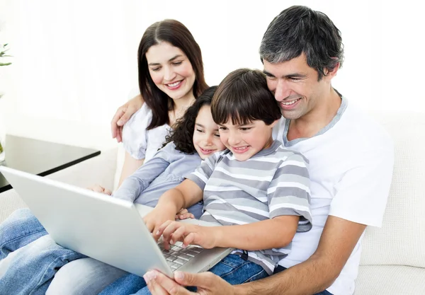 Família feliz usando um laptop sentado no sofá — Fotografia de Stock