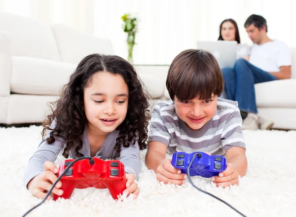 Cute siblings playing video games laying down on the floor — Stock Photo, Image