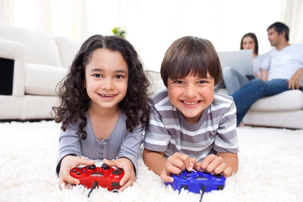 Ler syskon spelar TV-spel som ligger på golvet — Stockfoto