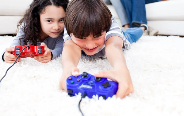 Веселые дети играют в видеоигры, лежащие на полу — стоковое фото