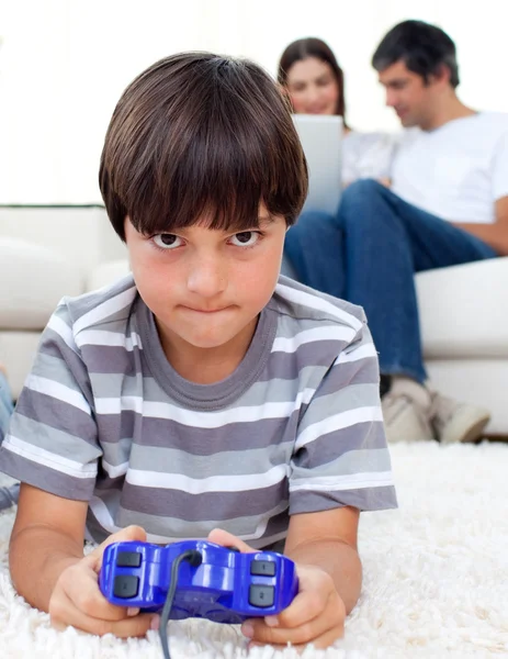 Konzentrierter Junge spielt Videospiele auf dem Boden liegend — Stockfoto