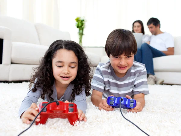 Jolly syskon spelar TV-spel som ligger på golvet — Stockfoto