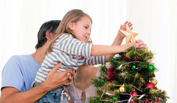 Klein meisje plaatsen van een ster in een kerstboom — Stockfoto