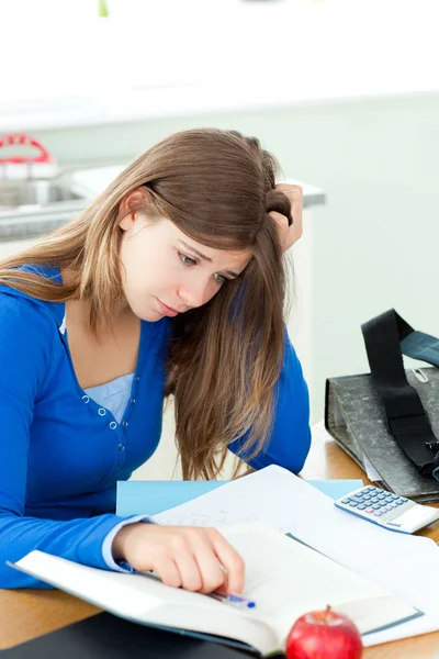 Стрессовая студентка делает домашнее задание на столе — стоковое фото