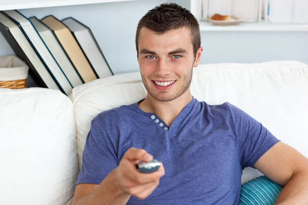 Uomo sorridente che si rilassa nel soggiorno guardando la televisione — Foto Stock