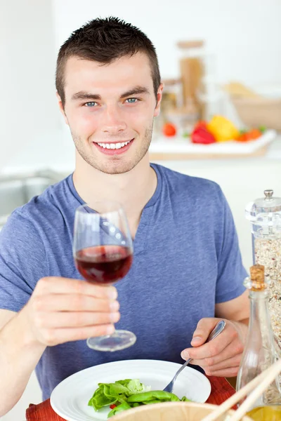 Cute man eating a healthy salad with some wine — Stock Photo, Image