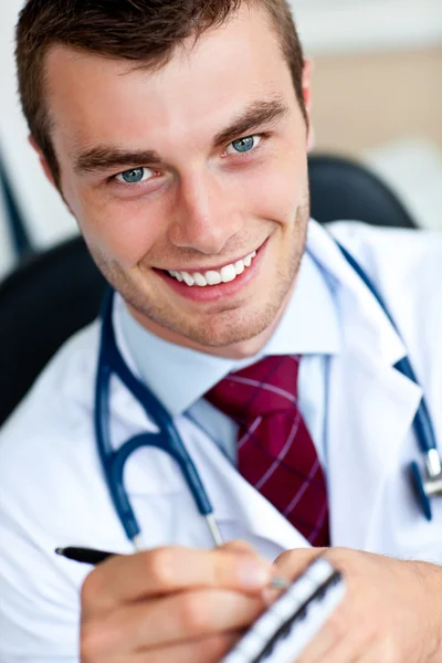 Sorrindo médico masculino escrevendo uma percrição — Fotografia de Stock