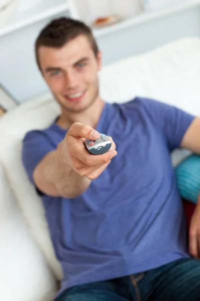 Young man is relaxing in the living-room with remote — Stock Photo, Image