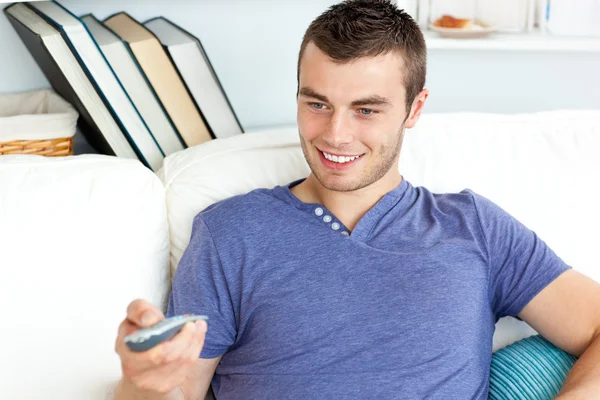 Schattig man is ontspannen in de woonkamer met afstandsbediening — Stockfoto