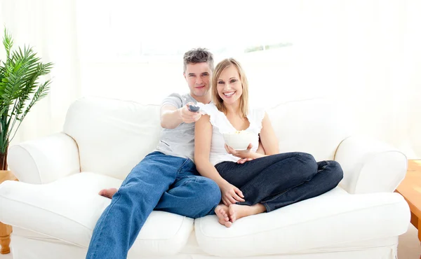Adorável casal usando um controle remoto na sala de estar — Fotografia de Stock