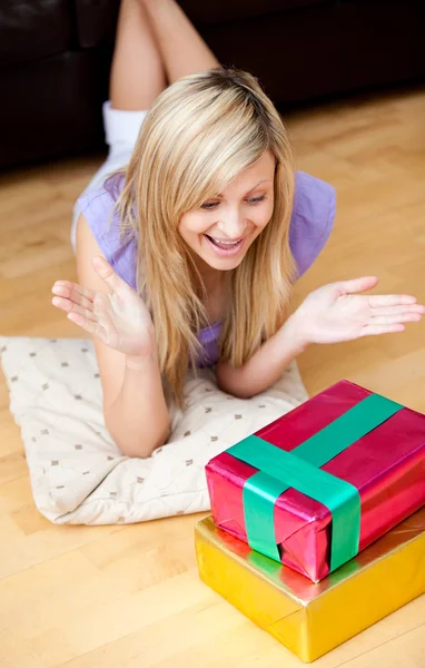 Zaskoczony, młoda kobieta, otwieranie prezentów na podłodze w pokoju dziennym — Zdjęcie stockowe