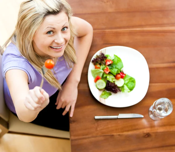 Portret van een mooie vrouw die het eten van een salade in de woonkamer — Stockfoto