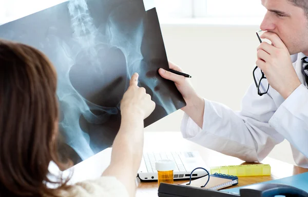 Médico analisando um raio-X com uma paciente do sexo feminino — Fotografia de Stock