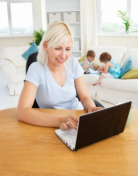 Занятая женщина работает со своими детьми за ноутбуком — стоковое фото