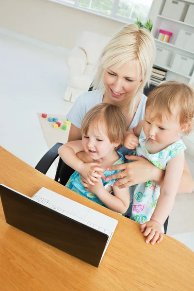 Сияющая женщина, работающая со своими детьми за ноутбуком — стоковое фото