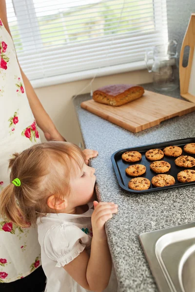 Menina gentil de pé na cozinha na frente dos biscoitos — Fotografia de Stock