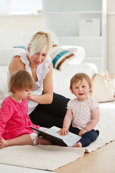 Good-looking woman working with her children at laptop — Stock Photo, Image
