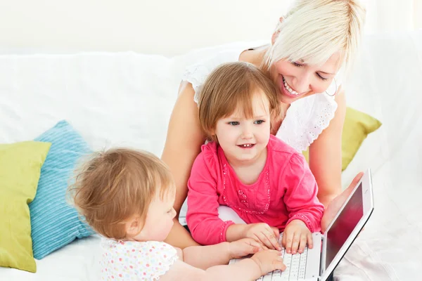 Smiling woman working with her children at laptop — Stock Photo, Image