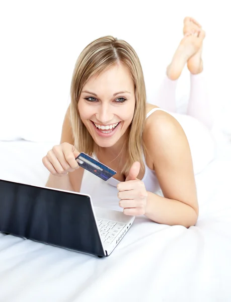 Śmiejąc się kobieta, leżąc z laptopem na kanapie — Zdjęcie stockowe
