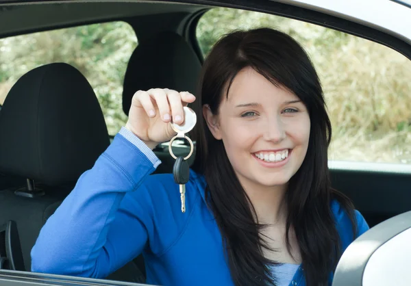 Сяючий підліток тримає ключі від машини, що сидить у її новій машині — стокове фото