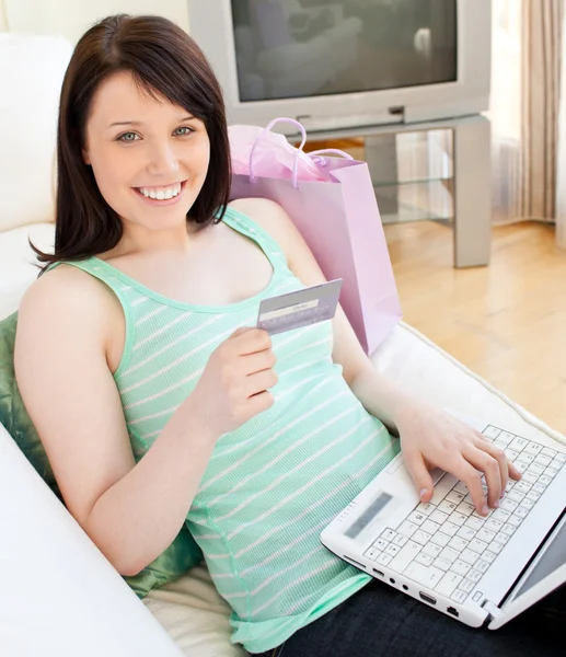 Brillante joven mujer holdign una tarjeta usando su computadora portátil — Foto de Stock