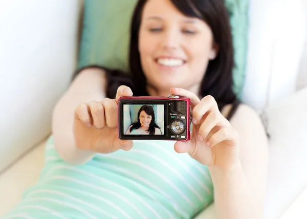 Attractive woman taking a picture of herself lying on bed — Stock Photo, Image