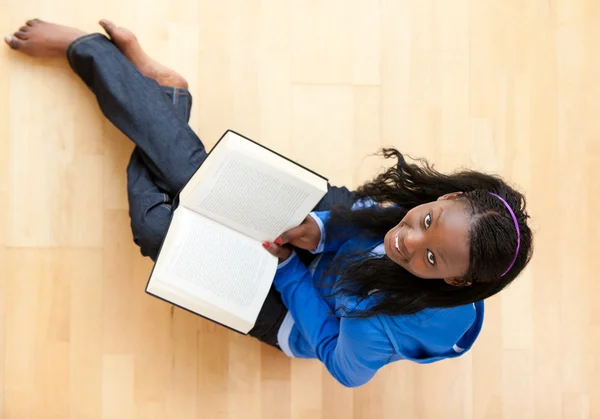 Delighted young woman looking up at the camera holidng a book — Stock Photo, Image