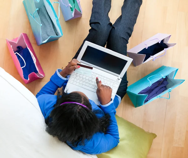 Досить афро-американський підліток використовує ноутбук, що сидить між взуттям — стокове фото