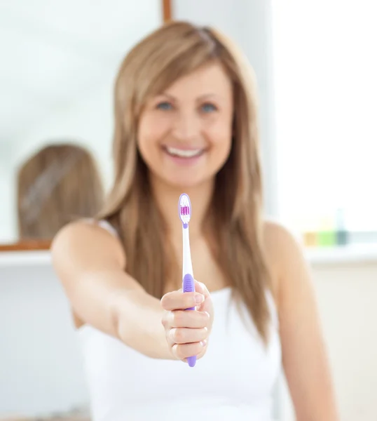 Donna sorridente che tiene uno spazzolino nella fotocamera — Foto Stock