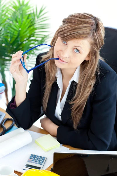 Femme d'affaires réfléchie tenant des lunettes assis à son bureau — Photo