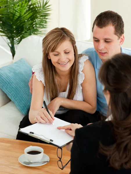 Bright young couple signing a contract sitting in their living r — Stock Photo, Image