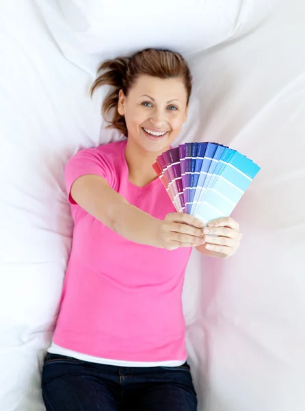 Delighted woman lying on a sofa holding color sample — Stock Photo, Image