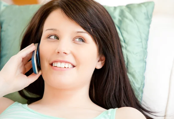 Красивая молодая женщина разговаривает по телефону лежа на диване — стоковое фото