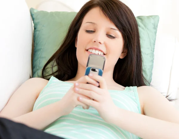 Encantado adolescente enviando uma mensagem de texto deitado no sofá — Fotografia de Stock