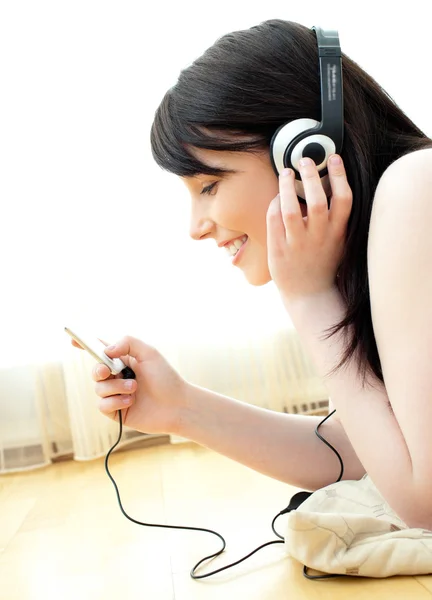 Glad ung kvinna lyssna på musik som ligger på golvet — Stockfoto