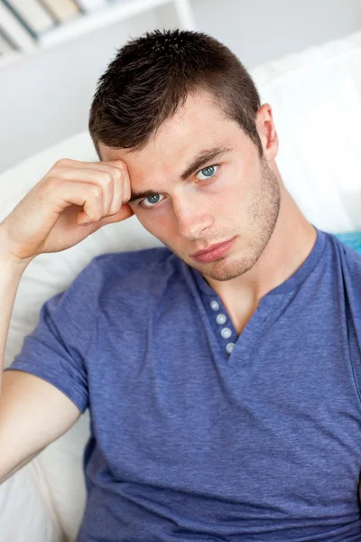 Депрессивный молодой человек сидит на диване — стоковое фото