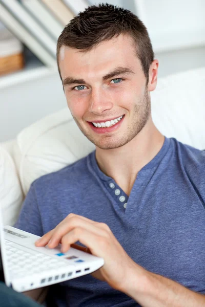 Счастливый человек сидит на диване с ноутбуком — стоковое фото