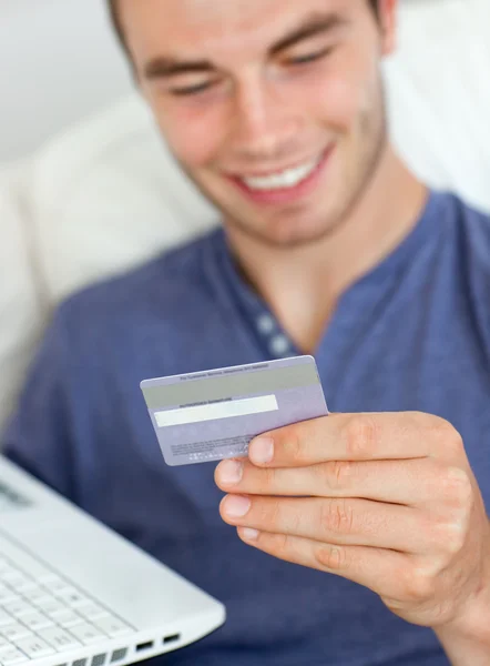 Close-up of a smiling man holding a card and a laptop — Stock Photo, Image