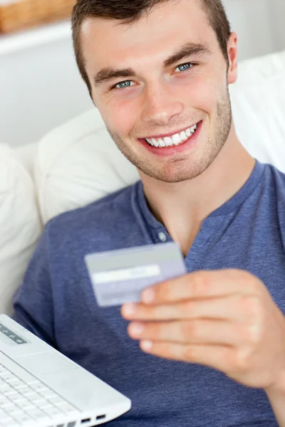 Primer plano de un hombre alegre sosteniendo una tarjeta y un ordenador portátil —  Fotos de Stock