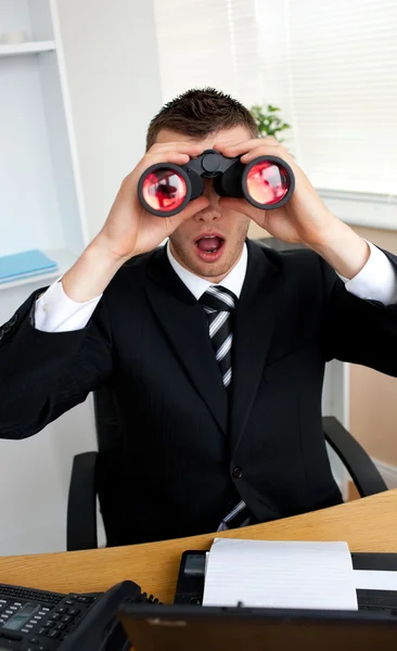Joven empresario asombrado mirando a través de binoluarios — Foto de Stock