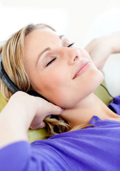 Mujer relajada escuchar música tumbada en un sofá —  Fotos de Stock