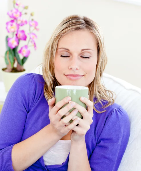 백인 금발 여자는 소파에 앉아 그녀의 커피를 즐길 수 — 스톡 사진
