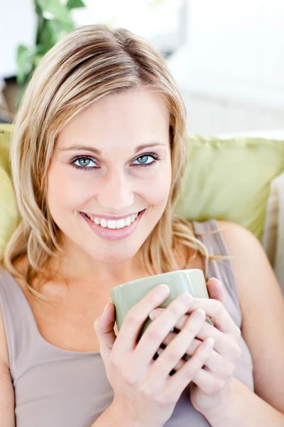 Mulher loira positiva segurando uma xícara sorrindo para a câmera — Fotografia de Stock