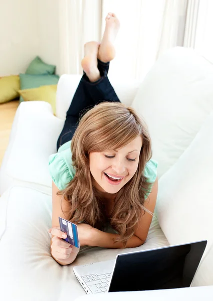 Mulher caucasiana alegre usando seu laptop segurando um cartão — Fotografia de Stock